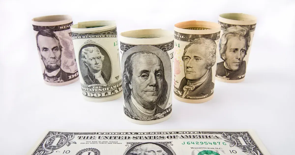 Rolled US dollar banknotes standing on a white table