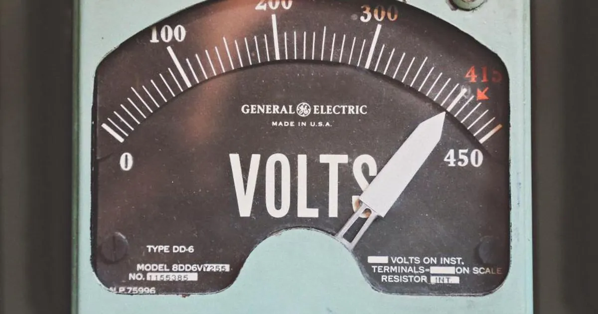 Close-up of a vintage electric meter dial with its needle pointing high on the volts scale