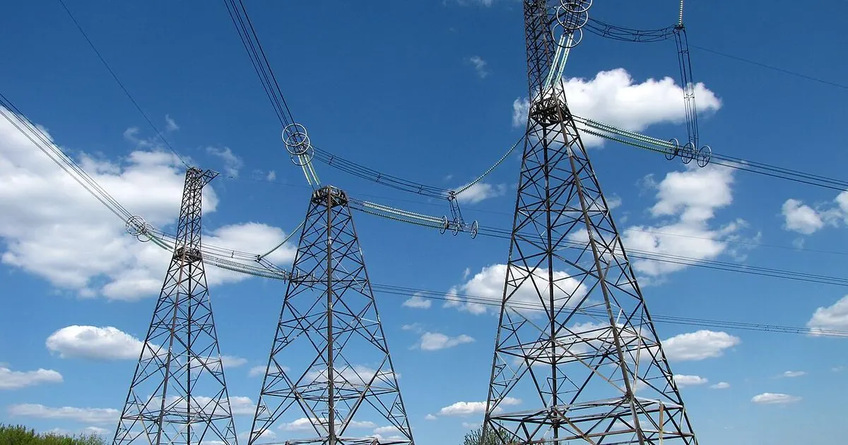 Steel high-voltage power line pylons against a blue sky