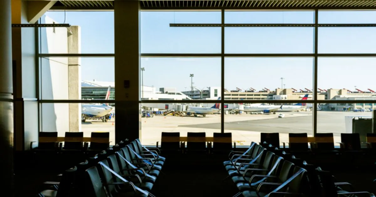 Empty seats in an airport departure lounge with parked planes outside the windows
