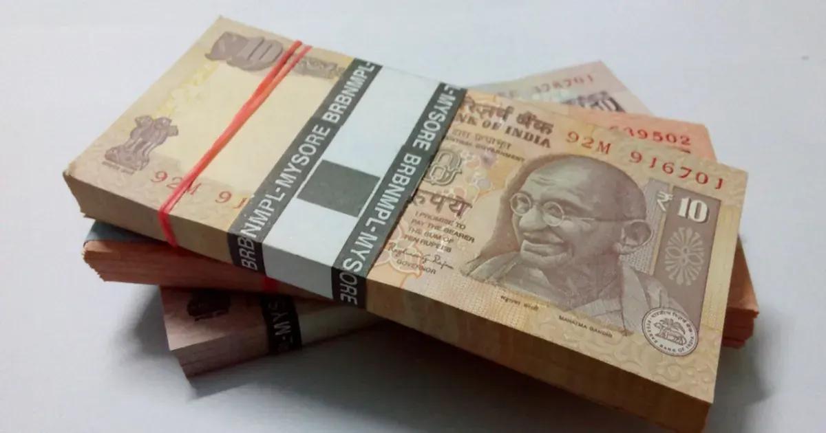 Bundles of Indian ten-rupee banknotes stacked on a white table