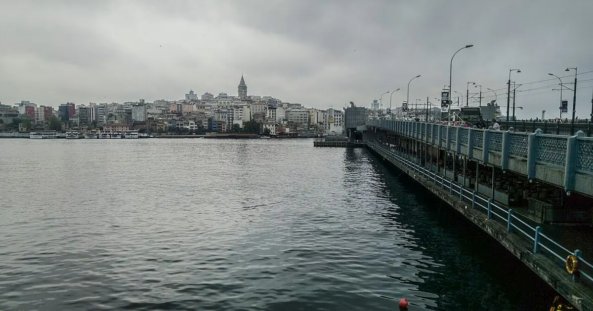 Galata Tower and the Istanbul waterfront under a grey, cloudy sky