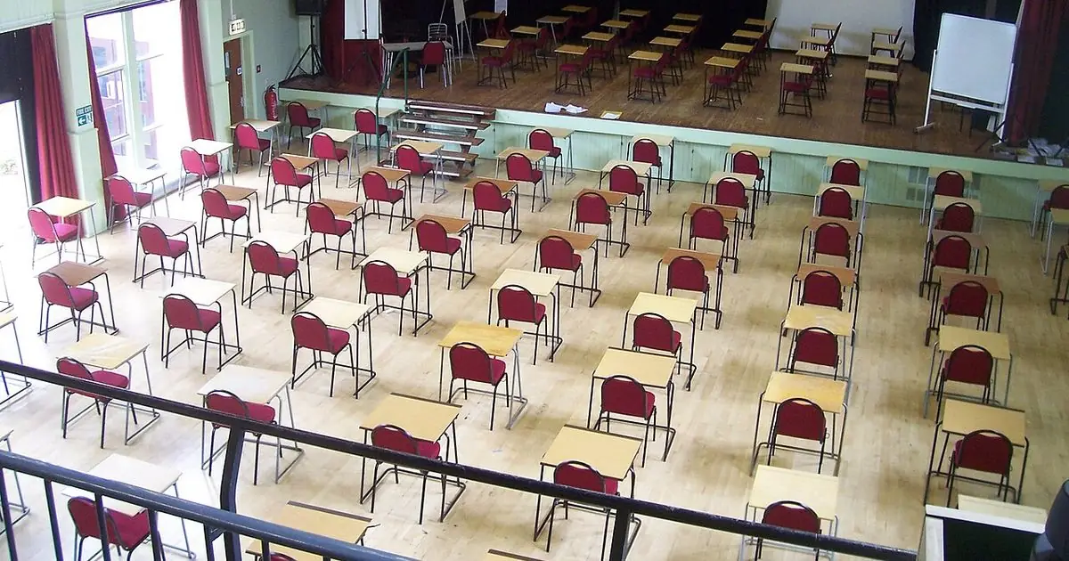 Rows of empty desks and chairs set out in a school examination hall