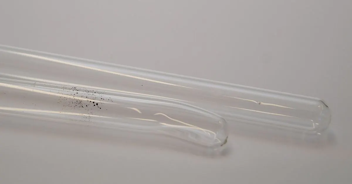 Two clear glass test tubes lying on a white surface