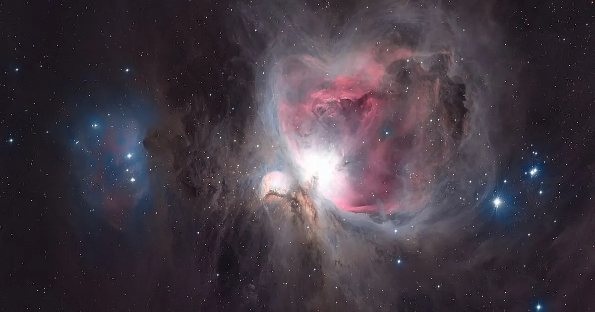 The Orion Nebula glowing pink and blue with bright young stars at its centre, against a dark starry sky