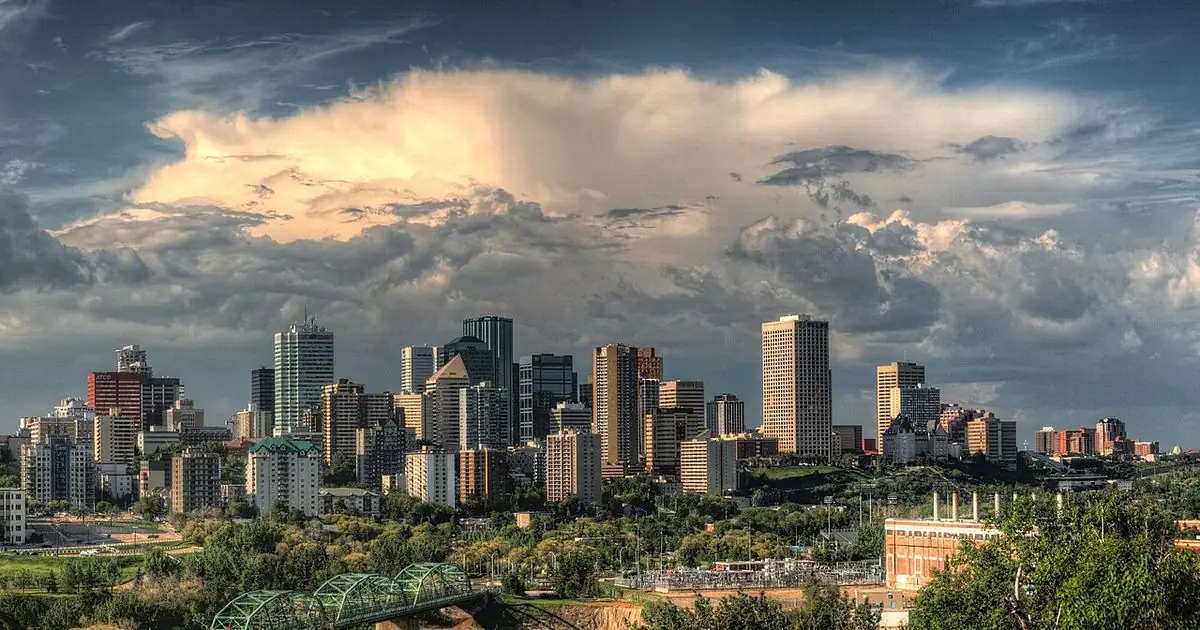 Downtown Edmonton skyline above the North Saskatchewan River valley under dramatic evening clouds