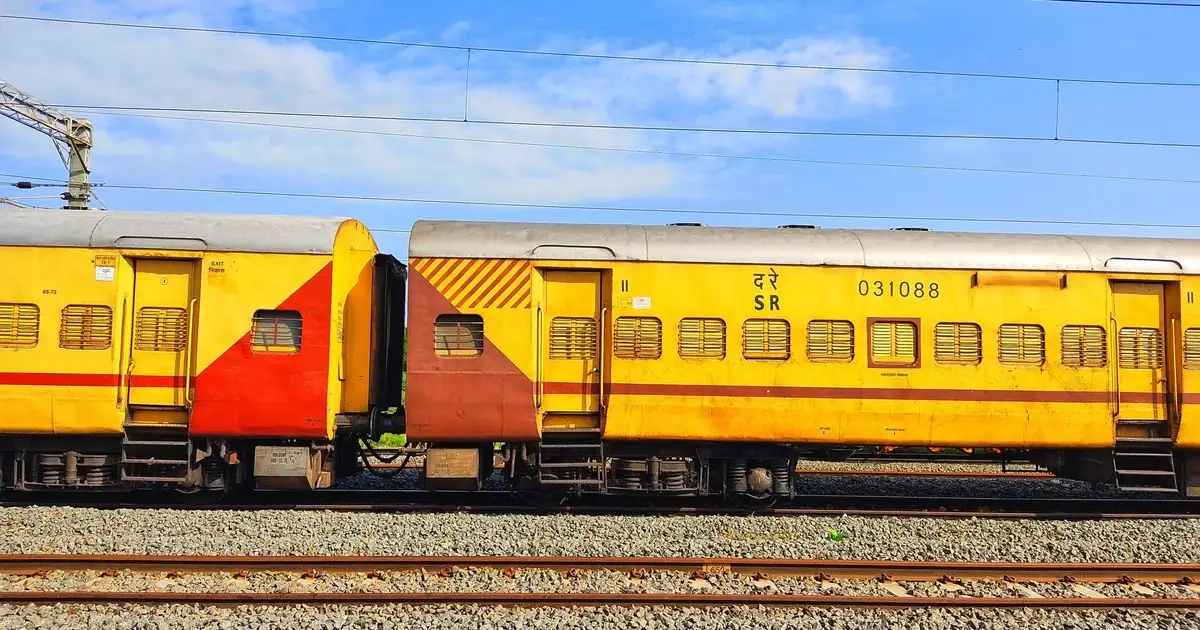 Yellow Indian Railways passenger coaches on a track under blue sky