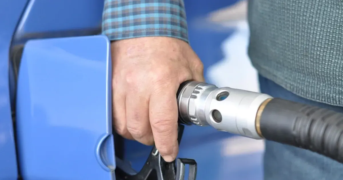 Hand holding a fuel nozzle while filling a car