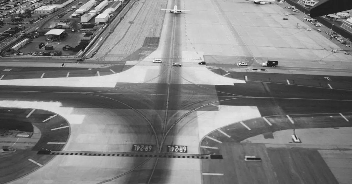 Aerial black-and-white view of an airport runway and taxiways