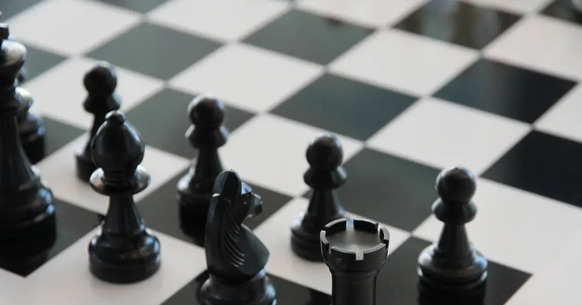 Staunton chess pieces arranged on a wooden chessboard