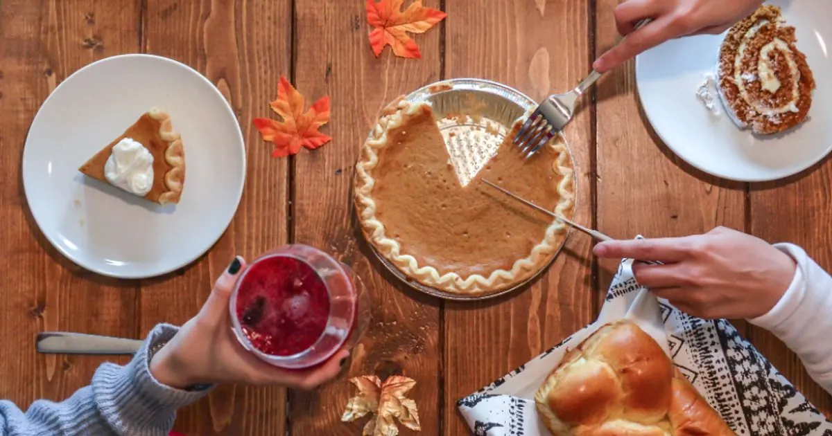 Pumpkin pie, bread and autumn leaves on a wooden Thanksgiving table