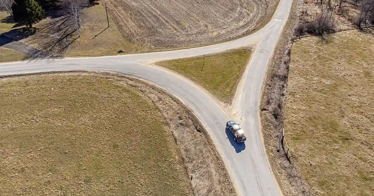 Forked dirt road splitting into two paths under open sky