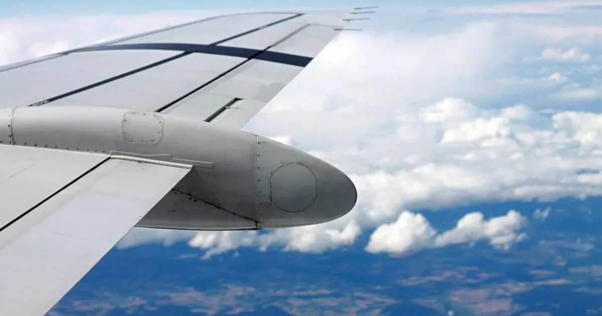 View of an airplane wing above white clouds from a passenger window