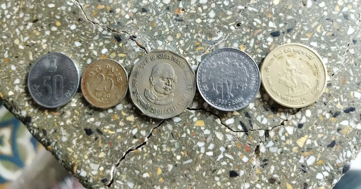 Five Indian rupee coins placed in a row on a stone surface