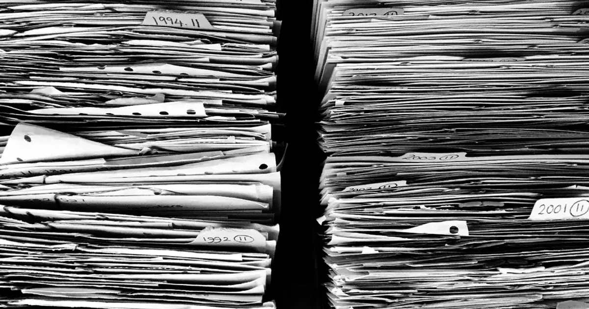 Stacks of paper files and documents piled together