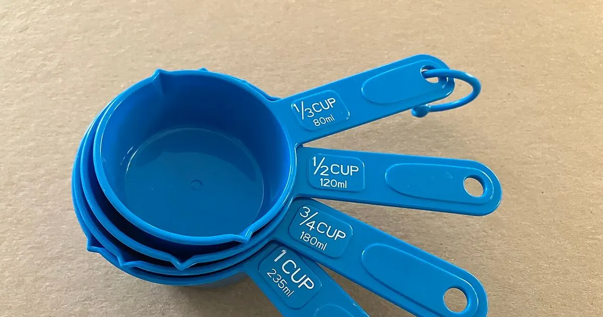 Set of blue plastic measuring cups nested together on a beige surface