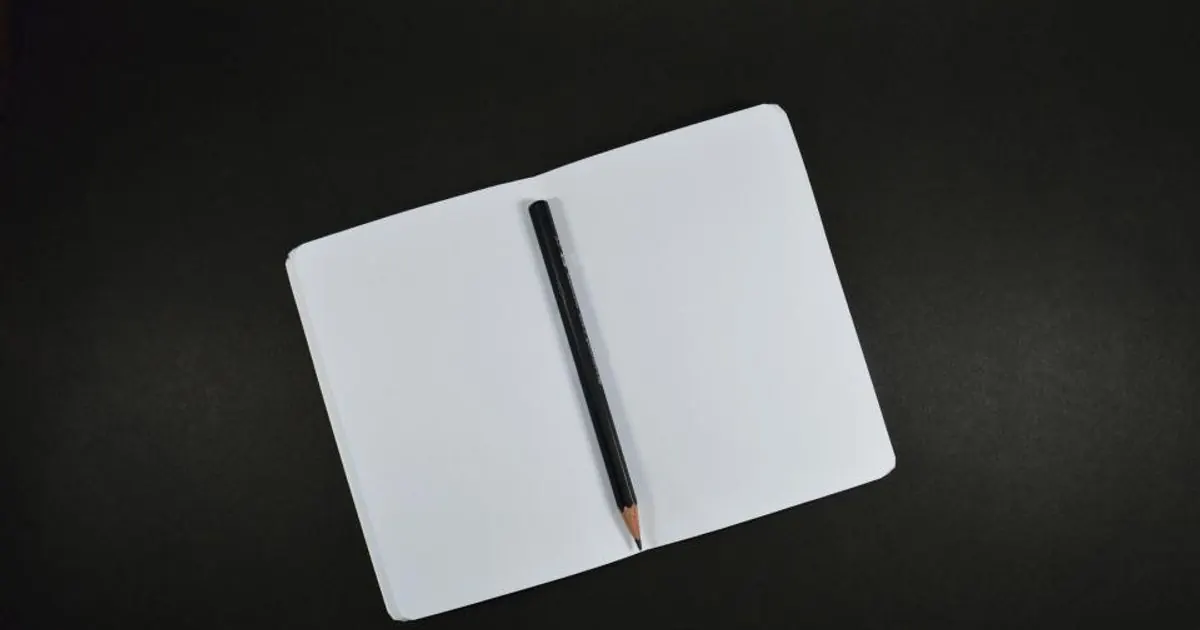 Pencil resting on a notepad on a wooden desk