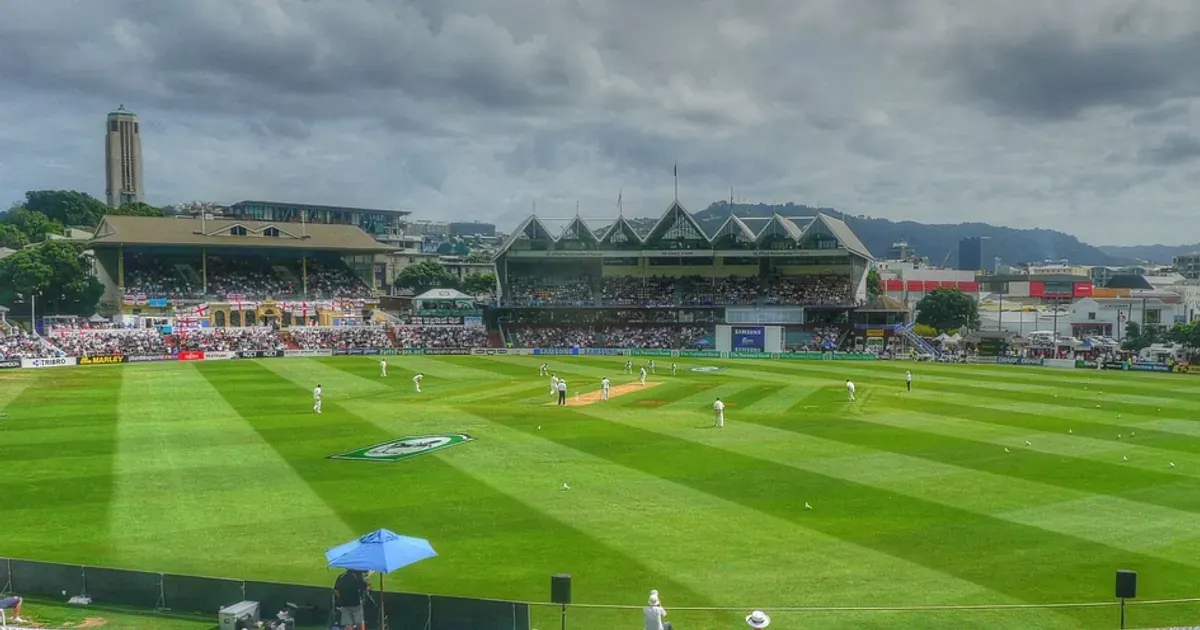 A cricket match under way at the Basin Reserve ground in Wellington, with stands and a cloudy sky