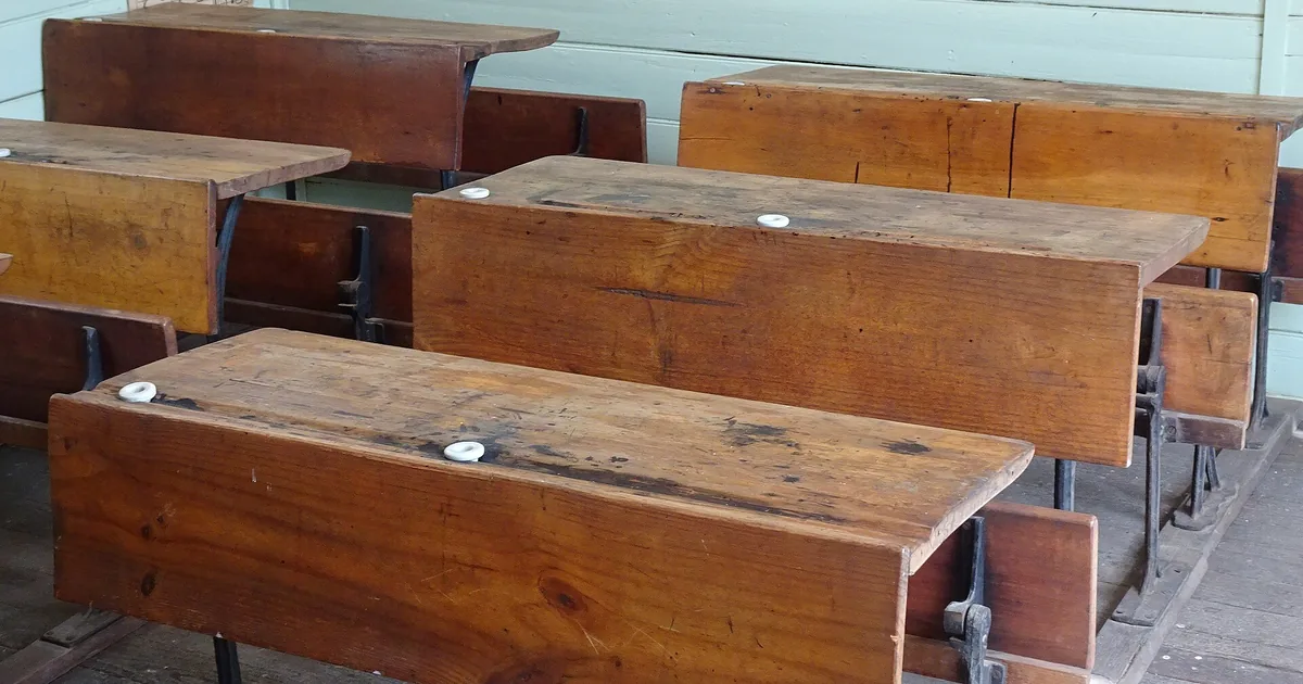 Rows of wooden school desks in a classroom