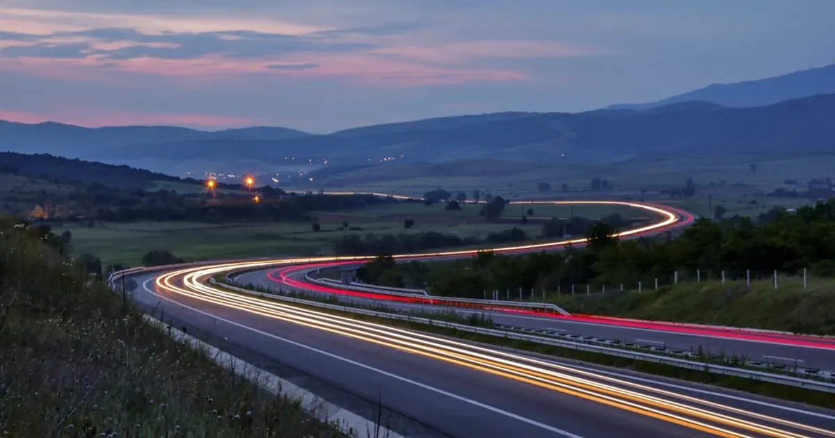 Long-exposure car light trails on a dark highway